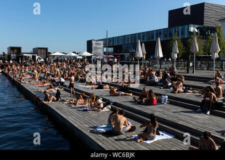 Et les touristes à la Futurama jetée en bois à Ofelia Square près de la Royal Play House (R) et l'historique Nyhavn à Copenhague, Danemark. L'eau dans le port de Copenhague est si propre qu'il est sûr de prendre un bain. En 2018, CNN en tête de Copenhague pour "liste des villes meilleures pour la natation". Banque D'Images