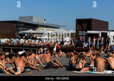 Et les touristes à la Futurama jetée en bois à Ofelia Square près de la Royal Play House (R) et l'historique Nyhavn à Copenhague, Danemark. L'eau dans le port de Copenhague est si propre qu'il est sûr de prendre un bain. En 2018, CNN en tête de Copenhague pour "liste des villes meilleures pour la natation". Banque D'Images