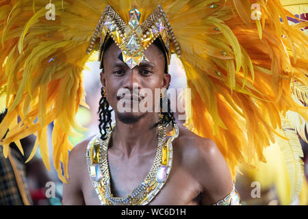 Un homme portant une plume jaune robe tête à Notting Hill Carnival. Banque D'Images