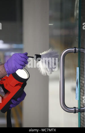 Close-up de l'agent de police de mains porter des gants de poudre pour les empreintes digitales Banque D'Images