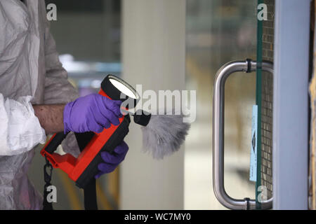 Close-up de l'agent de police de mains porter des gants de poudre pour les empreintes digitales Banque D'Images