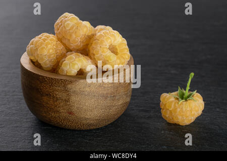 Beaucoup de frais mûrs ensemble golden hymalayan framboise au bol en bois sur la pierre grise Banque D'Images