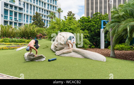Orlando, PF - 17 juin 2018 : deux personnes, un homme et une femme, sont la pratique du yoga sur 'l'utilisation de la découverte" statue par Meg White à Lake Eola Park Banque D'Images