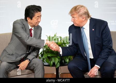 Le Président américain Donald Trump, serre la main avec le Premier ministre japonais Shinzo Abe, gauche, avant leur réunion commerciale en marge de sommet du G7 au centre de congrès Bellevue 25 août 2019 à Biarritz, France. Banque D'Images