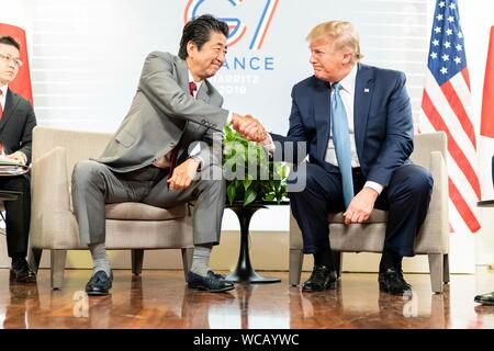 Le Président américain Donald Trump, serre la main avec le Premier ministre japonais Shinzo Abe, gauche, avant leur réunion commerciale en marge de sommet du G7 au centre de congrès Bellevue 25 août 2019 à Biarritz, France. Banque D'Images