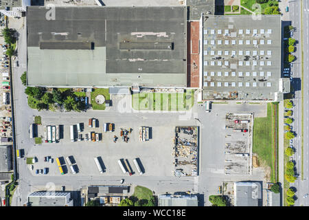 Vue du dessus de l'antenne d'un bâtiment industriel moderne et de l'entrepôt avec les camions et les voitures en stationnement photo drone. Banque D'Images