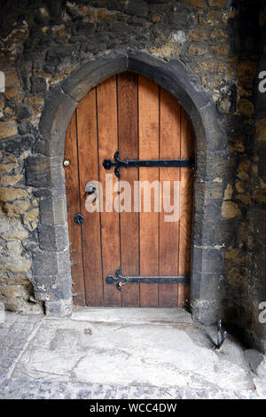 Une vieille porte en bois situé dans un son surround en pierre avec un racloir d'amorçage Banque D'Images
