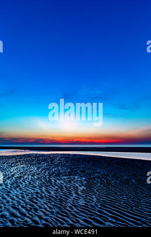 Ciel coloré sur la mer du Nord après le coucher du soleil sur la plage de Juist, îles de la Frise orientale, en Allemagne. Banque D'Images