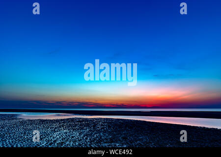 Ciel coloré sur la mer du Nord après le coucher du soleil sur la plage de Juist, îles de la Frise orientale, en Allemagne. Banque D'Images