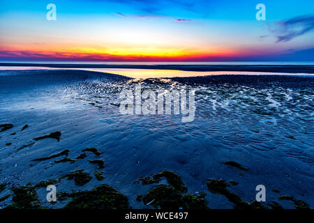 Ciel coloré sur la mer du Nord après le coucher du soleil sur la plage de Juist, îles de la Frise orientale, en Allemagne. Banque D'Images