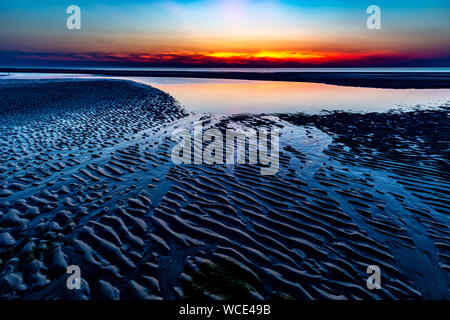 Ciel coloré sur la mer du Nord après le coucher du soleil sur la plage de Juist, îles de la Frise orientale, en Allemagne. Banque D'Images