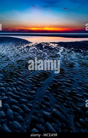 Ciel coloré sur la mer du Nord après le coucher du soleil sur la plage de Juist, îles de la Frise orientale, en Allemagne. Banque D'Images