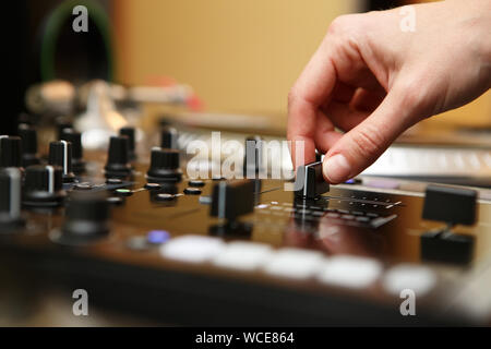 Mixage dj professionnel pistes musicales sur partie dans une boîte de nuit.Main de disc-jockey hip hop girl du réglage du volume sonore sur panneau Mélangeur.équipement de scène dans Banque D'Images