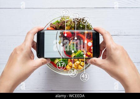 Compter les calories et de contrôle alimentaire concept. femme à l'aide d'application sur smartphone pour la numérisation de la quantité de calories dans la nourriture avant de manger Banque D'Images