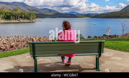 Dame sur le banc à la sur l'eau Banque D'Images