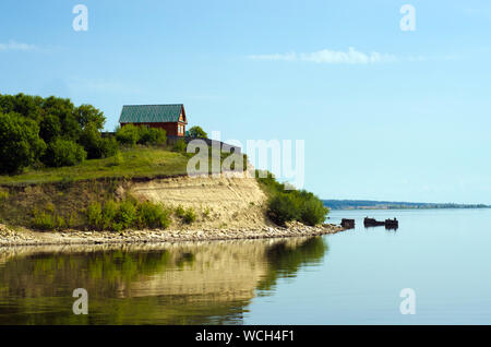 Beau paysage avec une maison en bois sur le bord d'une rivière avec la réflexion dans l'eau Banque D'Images