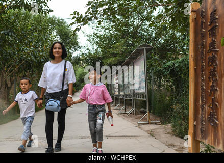 (190828) -- KASHGAR, 28 août 2019 (Xinhua) -- les villageois à pied dans une ruelle à Qianjin Village de Kashgar, dans la région autonome Uygur du Xinjiang, le 18 août 2019. Entouré d'habitations dans la profusion des fleurs parfumées, bien organisé et les ruelles de maisons une apparence soignée, une doublure d'arbres le long des rues où les enfants s'amusent, la scène pastorale peut être vu partout dans Qianjin Village. La beauté idyllique de Qianjin Village découle de sa fleur en plein essor de l'économie, dans lequel Salima Sultan est un pionnier. Salima, 60 ans, a mis au point l'affection des villageois de l'écoulement Banque D'Images