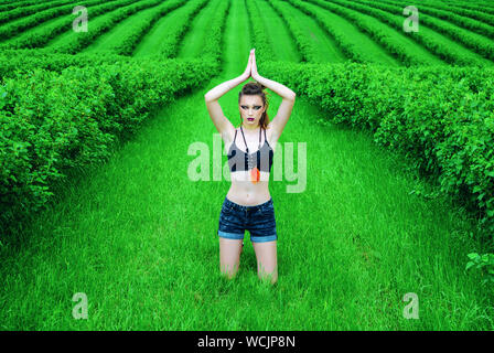 Cosplay girl maquillage agressif Viking dans un champ de blé vert. À genoux, priant pour les anciens dieux. Le Paganisme, le féminisme, l'indépendance, la tribu. Banque D'Images