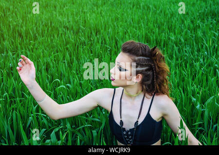 Make-up girl agressive bataille, peinture de la face de amazon dans un champ de blé vert parmi. Féminisme, indépendance, tribu. Banque D'Images