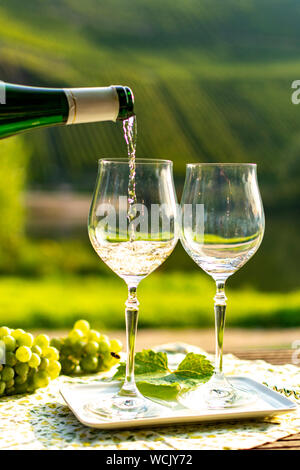 Waiter pouring qualité allemande du vin blanc riesling, produit en vin de Moselle regio raisins blancs poussant sur des pentes de collines dans la vallée de la rivière Mosel dans Banque D'Images