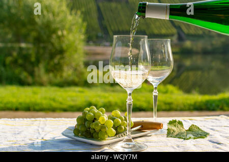 Waiter pouring qualité allemande du vin blanc riesling, produit en vin de Moselle regio raisins blancs poussant sur des pentes de collines dans la vallée de la rivière Mosel dans Banque D'Images