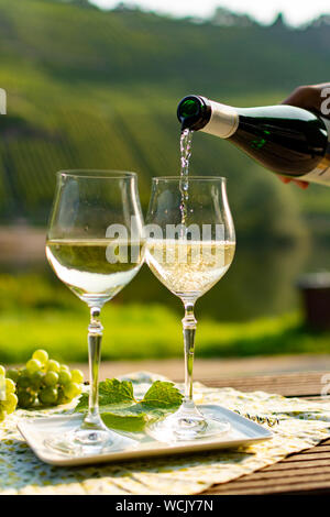 Waiter pouring qualité allemande du vin blanc riesling, produit en vin de Moselle regio raisins blancs poussant sur des pentes de collines dans la vallée de la rivière Mosel dans Banque D'Images