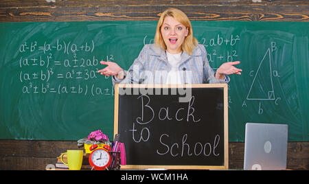 Monde numérique. L'école. L'enseignement à domicile. surpris femme. Retour à l'école. Journée des enseignants. femme en classe. enseignant avec réveil au tableau noir. Le temps. L'étude et l'éducation. L'école moderne. Jour des connaissances. Banque D'Images