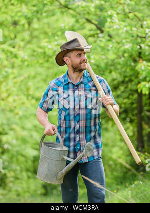 Jour de l'arbre. La plantation d'arbres. L'engagement et des responsabilités. Concept de l'agriculture. La plantation dans le jardin. La plantation de la tradition. Les plantes en croissance. Chapeau de cow-boy homme mûr avec arrosoir et pelle. Banque D'Images