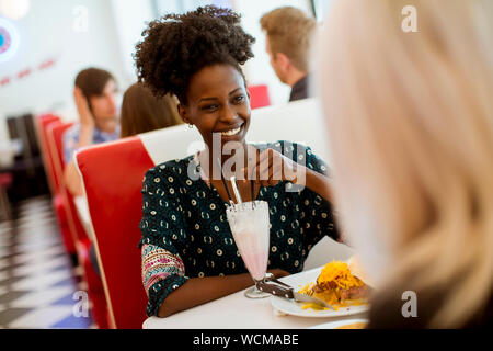 Les jeunes femmes multiraciales friends eating fast food à une table dans la salle à manger Banque D'Images