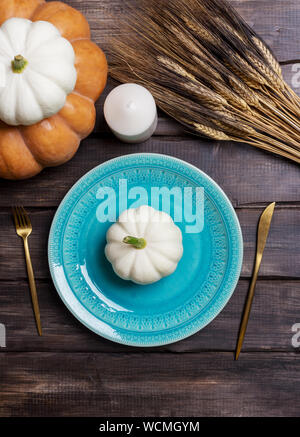 Assiette de service bleu bébé blanc avec squash sur elle, de la vaisselle d'or, une bougie et le blé sur la table en bois. Concept de l'ensemble de tables de récolte, pour manger Thanksg Banque D'Images