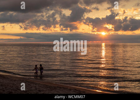 Union Pier, Michigan - Les enfants jouent alors que le soleil se couche sur le lac Michigan. Banque D'Images