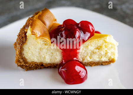 Close up d'une tranche de gâteau au fromage aux cerises Vue de côté et la sauce sur le dessus. Plaque blanche. Banque D'Images