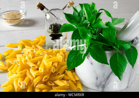 Pâtes penne, vert basilic, parmesan, le sésame, l'Ail, piment, les œufs se trouvent sur un arbre blanc tableau Banque D'Images