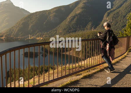 Une jeune femme aux cheveux blancs prend des photos avec son smartphone de Diablo Lake, dans la région de North Cascades Banque D'Images