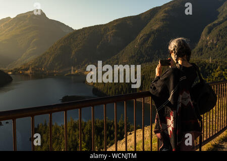 Une jeune femme aux cheveux blancs prend des photos avec son smartphone de Diablo Lake, dans la région de North Cascades Banque D'Images