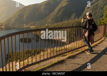 Une jeune femme aux cheveux blancs prend des photos avec son smartphone de Diablo Lake, dans la région de North Cascades Banque D'Images