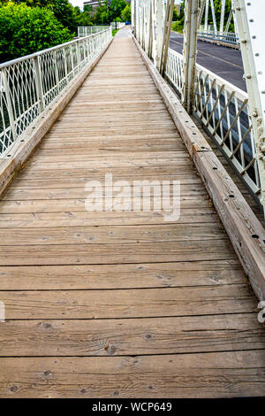 Une passerelle en bois s'étend depuis le trottoir et les piétons guides sur un pont blanc. Banque D'Images