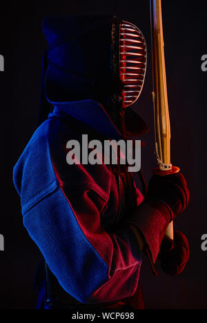 Close up shot, le Kendo fighter port d'une armure, casque, kimonos traditionnels pratiquant l'art martial avec shinai bamboo sword, fond noir. Banque D'Images