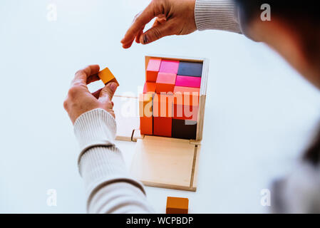 Les mains de l'enfant apprendre à mettre en place les pièces d'un puzzle en bois 3d. Banque D'Images