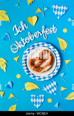 Texte papier 'J'aime' Oktoberfest en allemand, mise à plat sur le papier de fond avec bretzel sur plaques de papier décoratif, coeurs, drapeaux et les feuilles d'automne. Banque D'Images