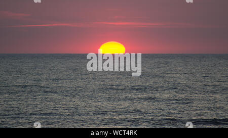 Le soleil qui touche l'horizon rouge. Banque D'Images