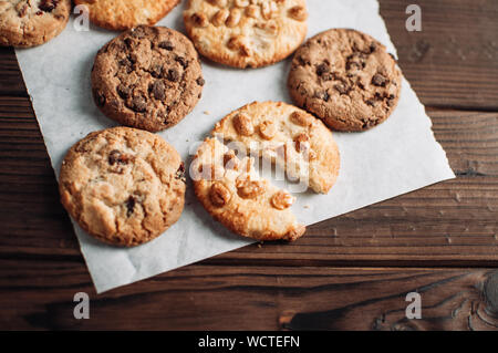 Les cookies au chocolat sur le papier parchemin. Broken biscuits sur une table en bois. Focus sélectif. Banque D'Images