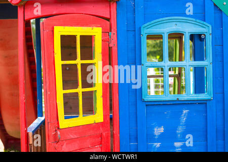Une petite maison en bois pour les enfants. La chambre est peinte avec des couleurs vives en bleu, jaune et rouge. Banque D'Images