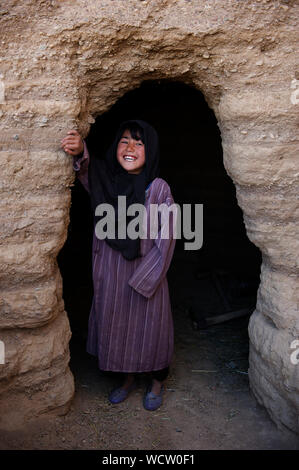 Une jeune fille se dresse à l'entrée d'une grotte où sa famille à garder le bétail pour les garder au chaud près de sa maison, dans le village de Rag-e-Shad, à la périphérie de la ville de Bamyan, dans le centre de la province de Bamyan, en Afghanistan. Le 11 mai 2009. Banque D'Images