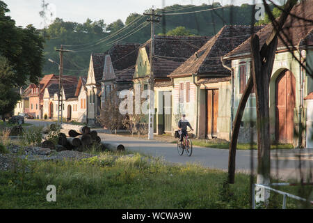 Des cyclistes et des maisons de la rue principale du village de Malancrav, Transylvanie, Roumanie Banque D'Images