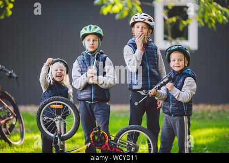 Les enfants de la mécanique, la réparation de bicyclettes. Enfants heureux ensemble vélo fixation à l'extérieur dans les jours ensoleillés. Concept de réparation de vélos. Avec des outils d'équipe family posing Banque D'Images