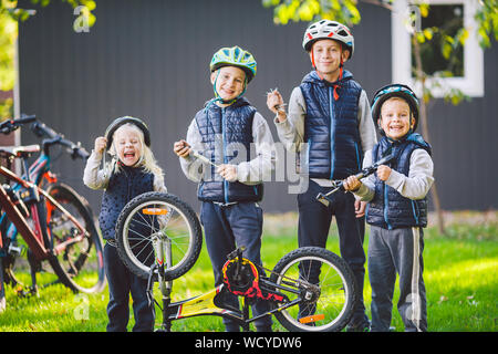 Les enfants de la mécanique, la réparation de bicyclettes. Enfants heureux ensemble vélo fixation à l'extérieur dans les jours ensoleillés. Concept de réparation de vélos. Avec des outils d'équipe family posing Banque D'Images