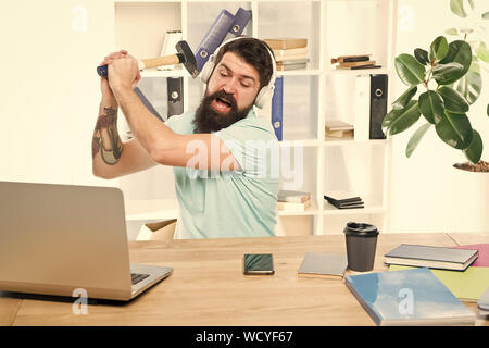 Connexion internet lente. Logiciel obsolète. Décalage de l'ordinateur. Pour des raisons du retard de l'ordinateur. Comment fixer la traîne lente du système. La routine du bureau. Homme barbu bureau écouteurs swing marteau sur ordinateur. Banque D'Images