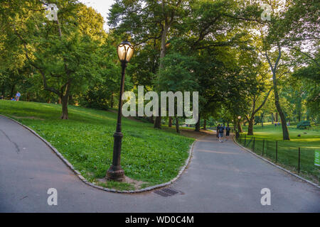 Vue panoramique avec des gens le vélo et la marche le long de la célèbre Central Park à New York au coucher du soleil. Banque D'Images