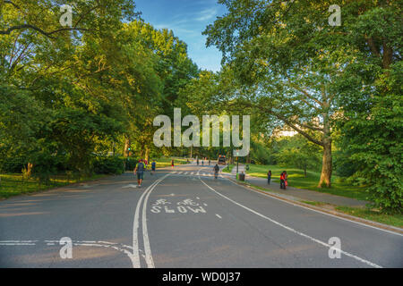 Vue panoramique avec des gens le vélo et la marche le long de la célèbre Central Park à New York au coucher du soleil. Banque D'Images